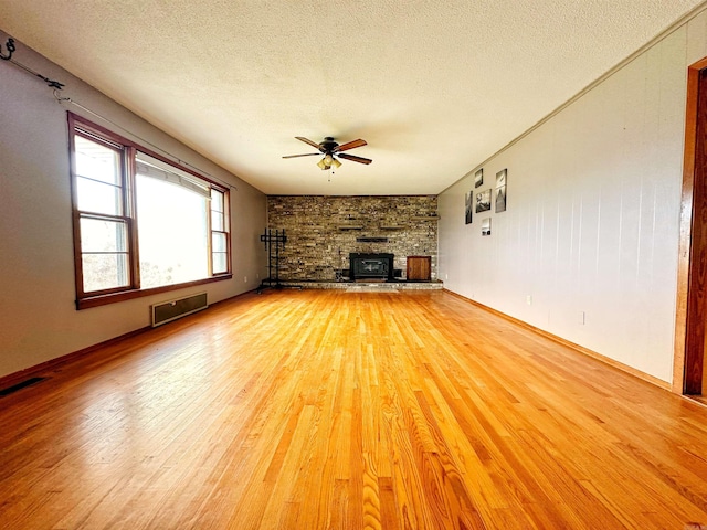 40 Sutton Ln, Batesville, AR 72501 - unfurnished living room with a ceiling fan, a textured ceiling, light wood-type flooring, a fireplace, and visible vents