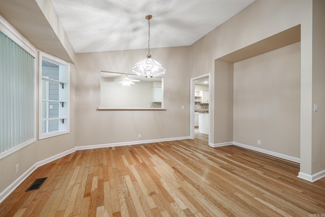 unfurnished dining area featuring baseboards, lofted ceiling, light wood finished floors, and visible vents