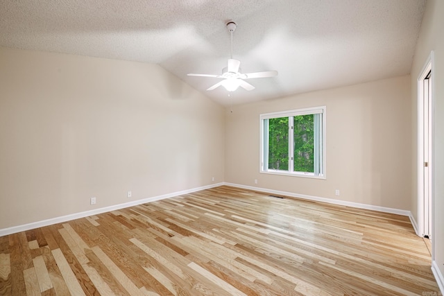 empty room featuring vaulted ceiling, baseboards, a ceiling fan, and light wood-style floors
