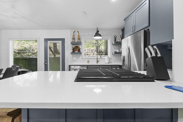 kitchen featuring tasteful backsplash, open shelves, a sink, stainless steel appliances, and light countertops
