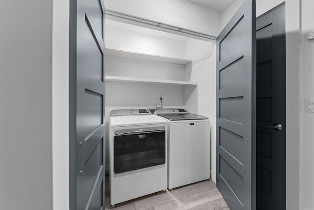 laundry area featuring separate washer and dryer, light wood-style floors, and laundry area
