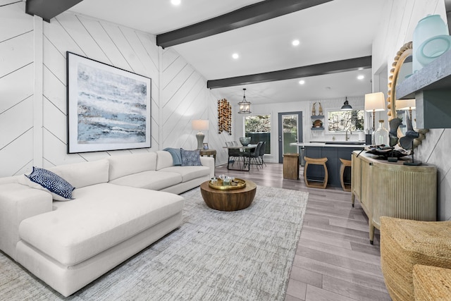 living room featuring recessed lighting, light wood-type flooring, wood walls, and lofted ceiling with beams