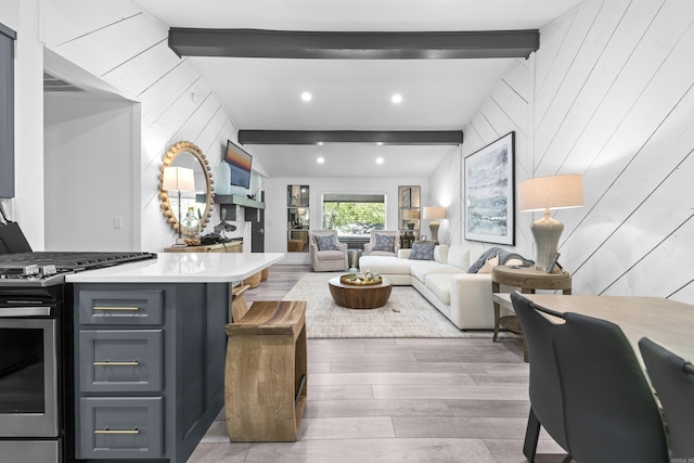 living area with wood walls, beam ceiling, and wood finished floors