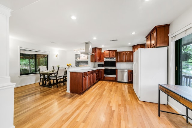2312 Breckenridge Dr, Little Rock, AR 72227 - kitchen with island range hood, light countertops, light wood-style flooring, a peninsula, and appliances with stainless steel finishes