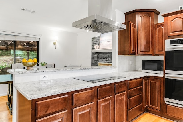 2312 Breckenridge Dr, Little Rock, AR 72227 - kitchen with black electric cooktop, light wood-type flooring, exhaust hood, light stone counters, and double oven