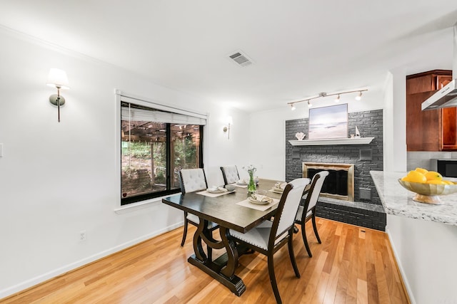 2312 Breckenridge Dr, Little Rock, AR 72227 - dining room with track lighting, visible vents, baseboards, light wood-style flooring, and a brick fireplace