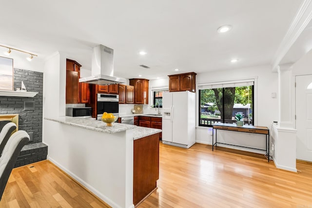 2312 Breckenridge Dr, Little Rock, AR 72227 - kitchen with a peninsula, island exhaust hood, a sink, light wood-style floors, and appliances with stainless steel finishes
