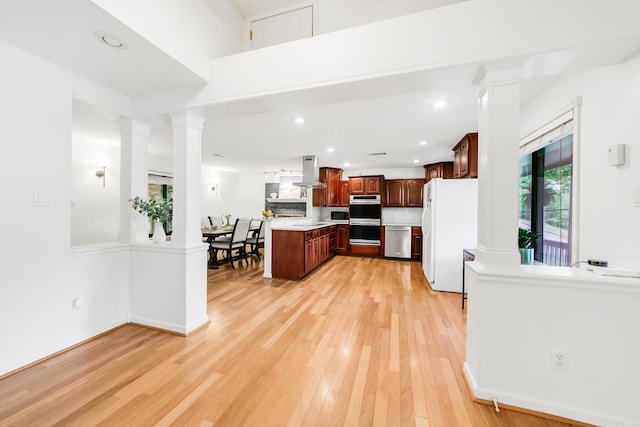2312 Breckenridge Dr, Little Rock, AR 72227 - kitchen featuring light wood-type flooring, ornate columns, island range hood, light countertops, and appliances with stainless steel finishes