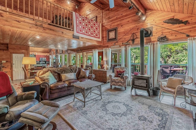 living room with wooden ceiling, beamed ceiling, a wood stove, and wooden walls