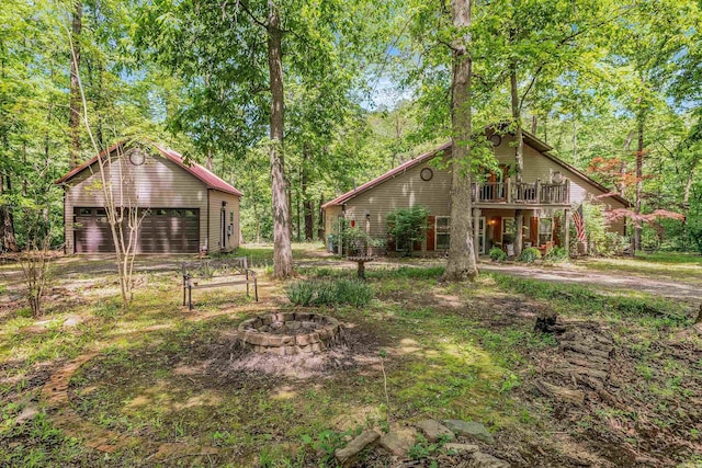 exterior space featuring stairway, a detached garage, a deck, an outdoor fire pit, and an outdoor structure