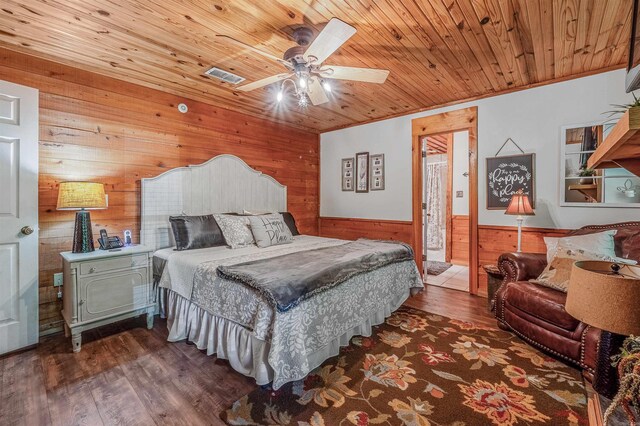 bedroom with a wainscoted wall, wooden walls, wood finished floors, visible vents, and wooden ceiling