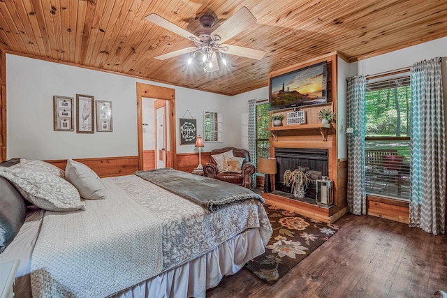 bedroom featuring wooden walls, wood finished floors, wood ceiling, and wainscoting