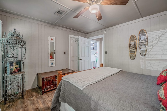bedroom featuring wood finished floors, visible vents, a ceiling fan, and wood walls