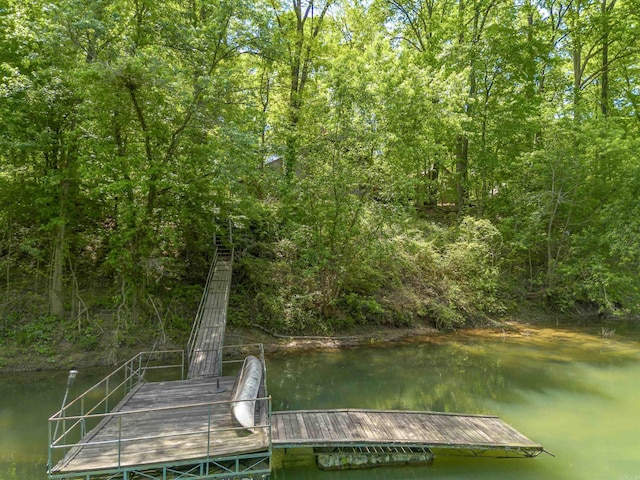view of dock with a wooded view and a water view