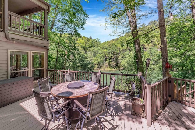 wooden terrace featuring a view of trees and outdoor dining space