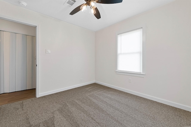 unfurnished room featuring carpet, visible vents, a ceiling fan, and baseboards