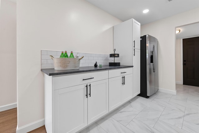 kitchen featuring dark countertops, white cabinets, backsplash, and stainless steel fridge with ice dispenser
