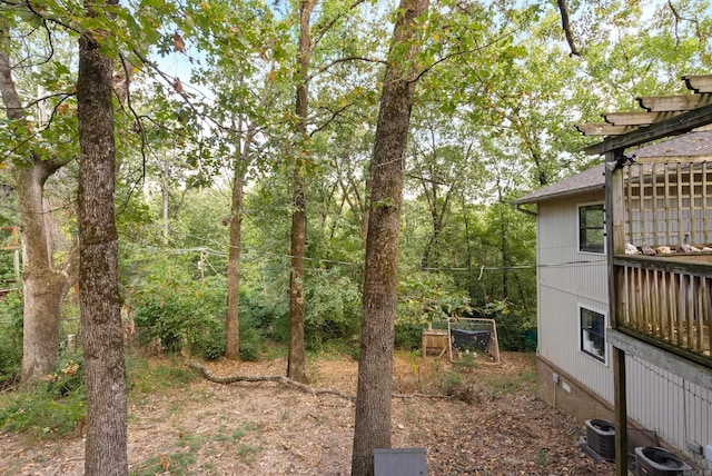 view of yard with central air condition unit and a forest view
