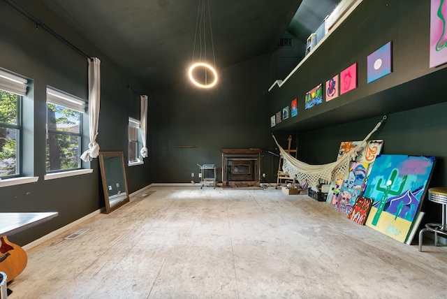 rec room with a wood stove, visible vents, a chandelier, and baseboards
