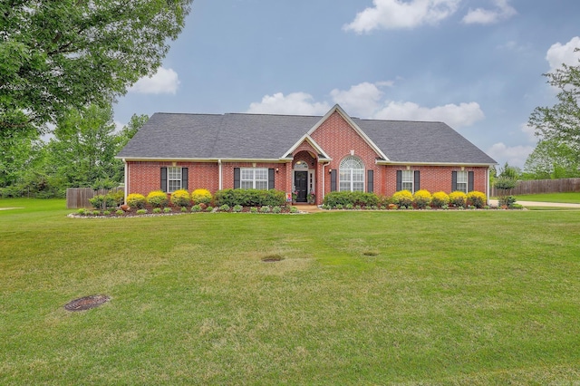 single story home featuring a front lawn, fence, a shingled roof, and brick siding
