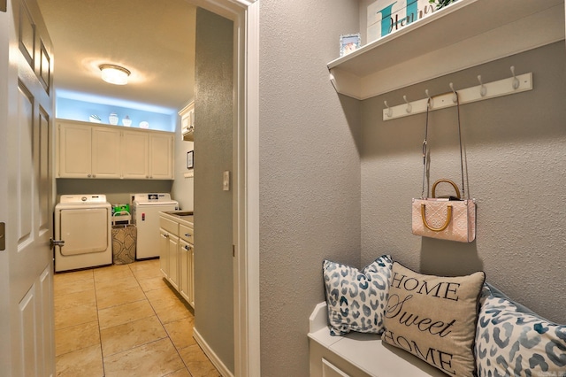 interior space featuring light tile patterned floors, cabinet space, washing machine and clothes dryer, and a textured wall