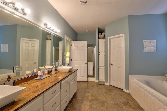 bathroom with double vanity, a bath, a stall shower, and a sink
