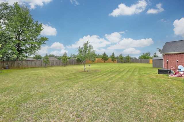 view of yard with a fenced backyard, a shed, and an outbuilding