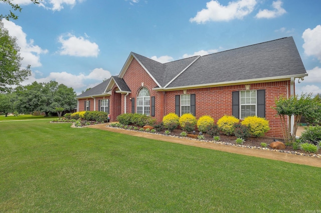 ranch-style home with a front lawn, a shingled roof, and brick siding