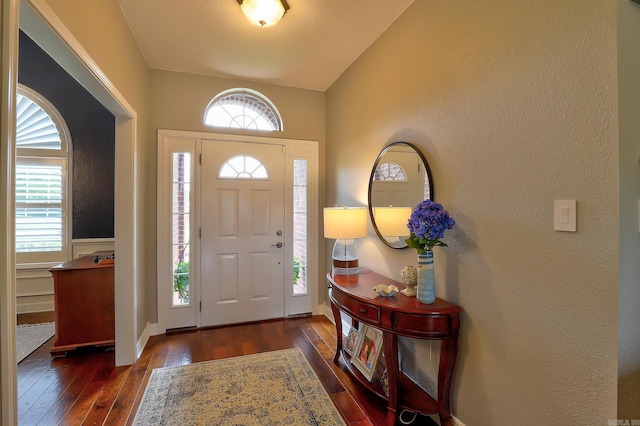 entrance foyer with dark wood-type flooring and a textured wall