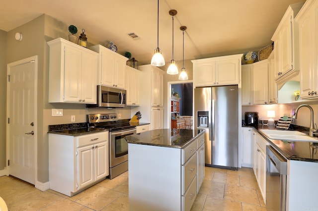 kitchen with appliances with stainless steel finishes, a center island, white cabinets, and a sink
