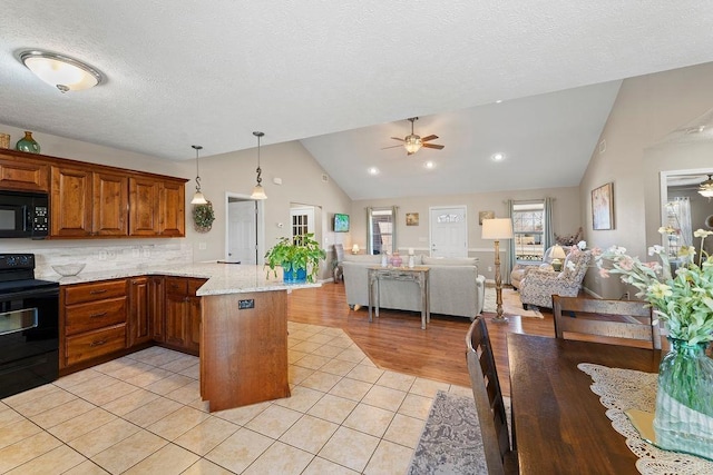 kitchen with ceiling fan, black appliances, open floor plan, vaulted ceiling, and a peninsula