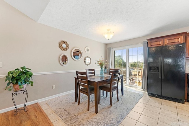 dining space featuring baseboards, light tile patterned floors, and a textured ceiling