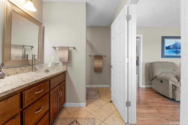 bathroom with baseboards, a textured ceiling, tile patterned flooring, and vanity