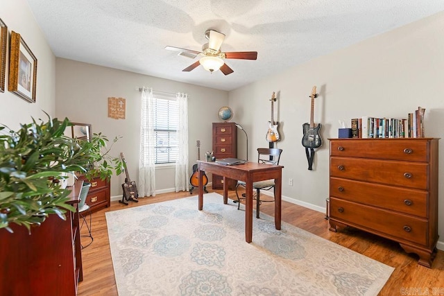 office space with a ceiling fan, baseboards, a textured ceiling, and light wood-type flooring