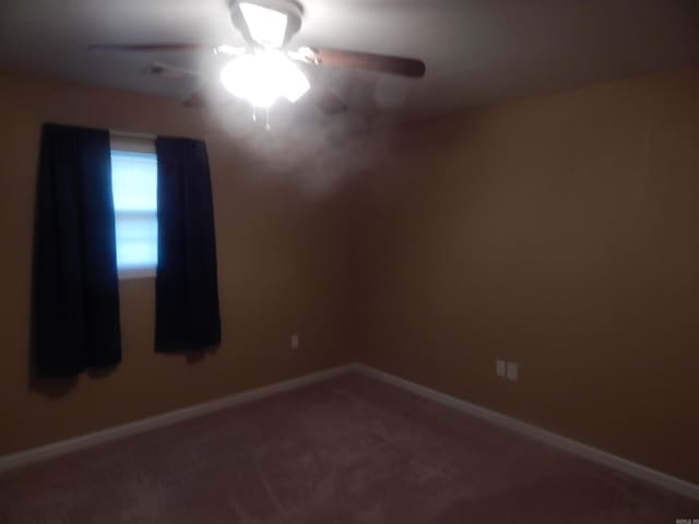 carpeted empty room with a ceiling fan and baseboards