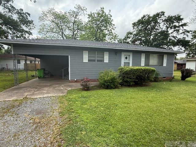 view of front of home featuring fence, a carport, gravel driveway, and a front yard