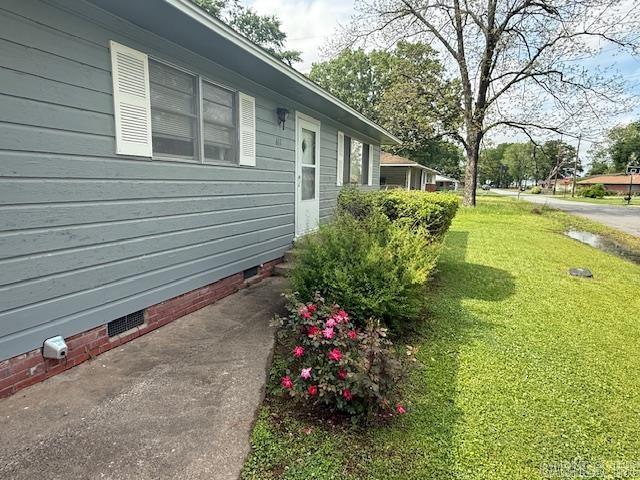 view of side of property featuring a lawn and crawl space