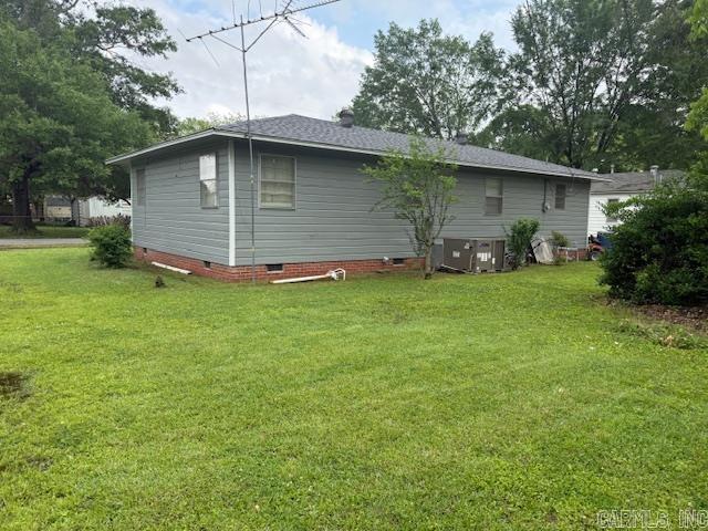 rear view of property featuring roof with shingles, central AC unit, a yard, and crawl space