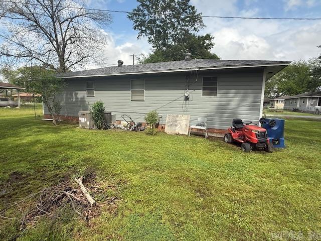 back of property featuring a yard and roof with shingles