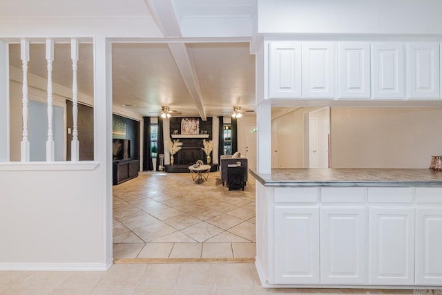 8033 Renee Cir, Benton, AR 72019 - kitchen featuring white cabinets, beamed ceiling, ceiling fan, light tile patterned flooring, and a stone fireplace