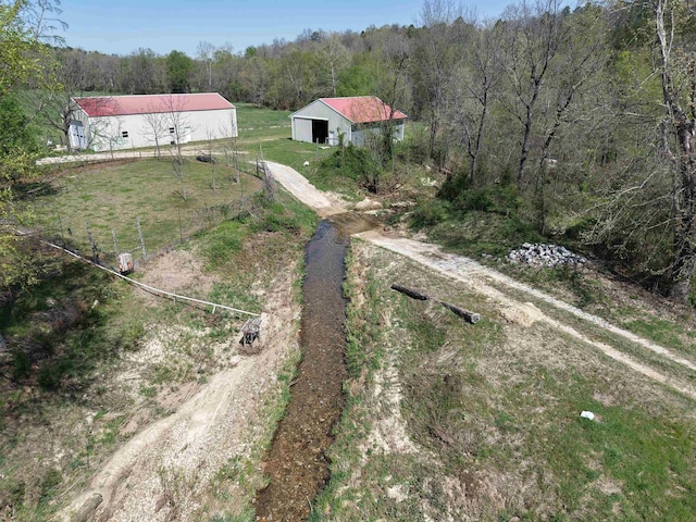 2157 Pleasant Grove Rd, Wideman, AR 72585 - view of yard featuring an outdoor structure, dirt driveway, a pole building, fence, and a forest view
