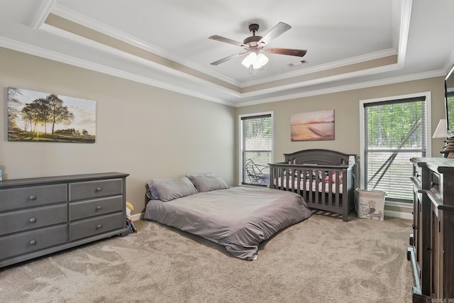 bedroom with crown molding, carpet flooring, visible vents, a tray ceiling, and a ceiling fan