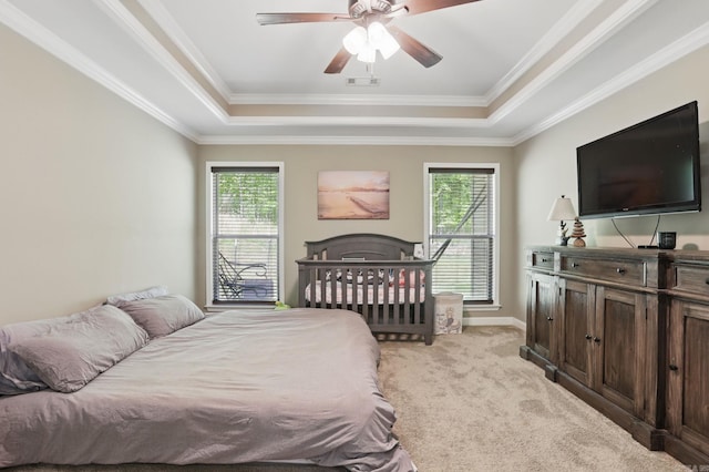 bedroom with light colored carpet, visible vents, multiple windows, and a tray ceiling