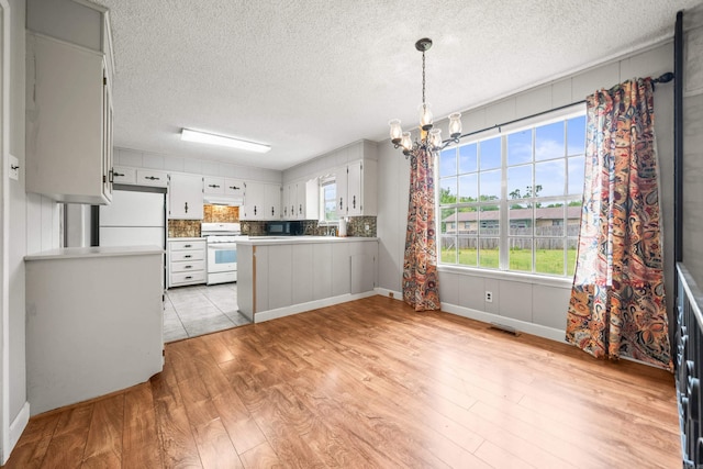 kitchen featuring fridge, a chandelier, light countertops, white range, and visible vents