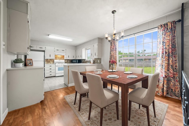 dining space with light wood finished floors and a notable chandelier