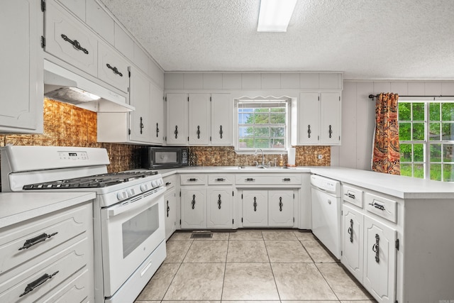 kitchen with white appliances, a peninsula, under cabinet range hood, backsplash, and a textured ceiling