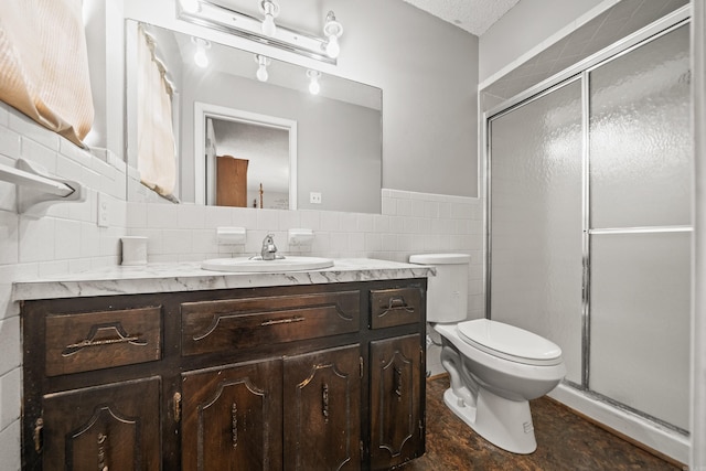bathroom with toilet, vanity, a shower stall, and tile walls
