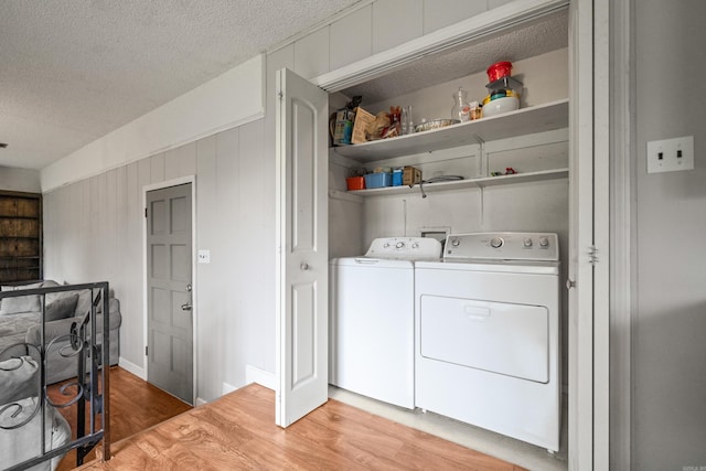 laundry room with washer and dryer, light wood-style flooring, laundry area, and a textured ceiling
