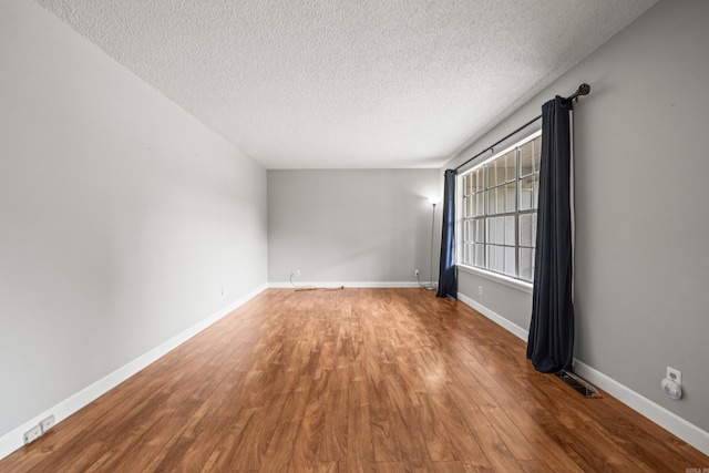 unfurnished room with baseboards, visible vents, wood finished floors, and a textured ceiling