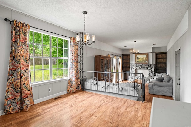 dining room with a textured ceiling, an inviting chandelier, wood finished floors, and visible vents